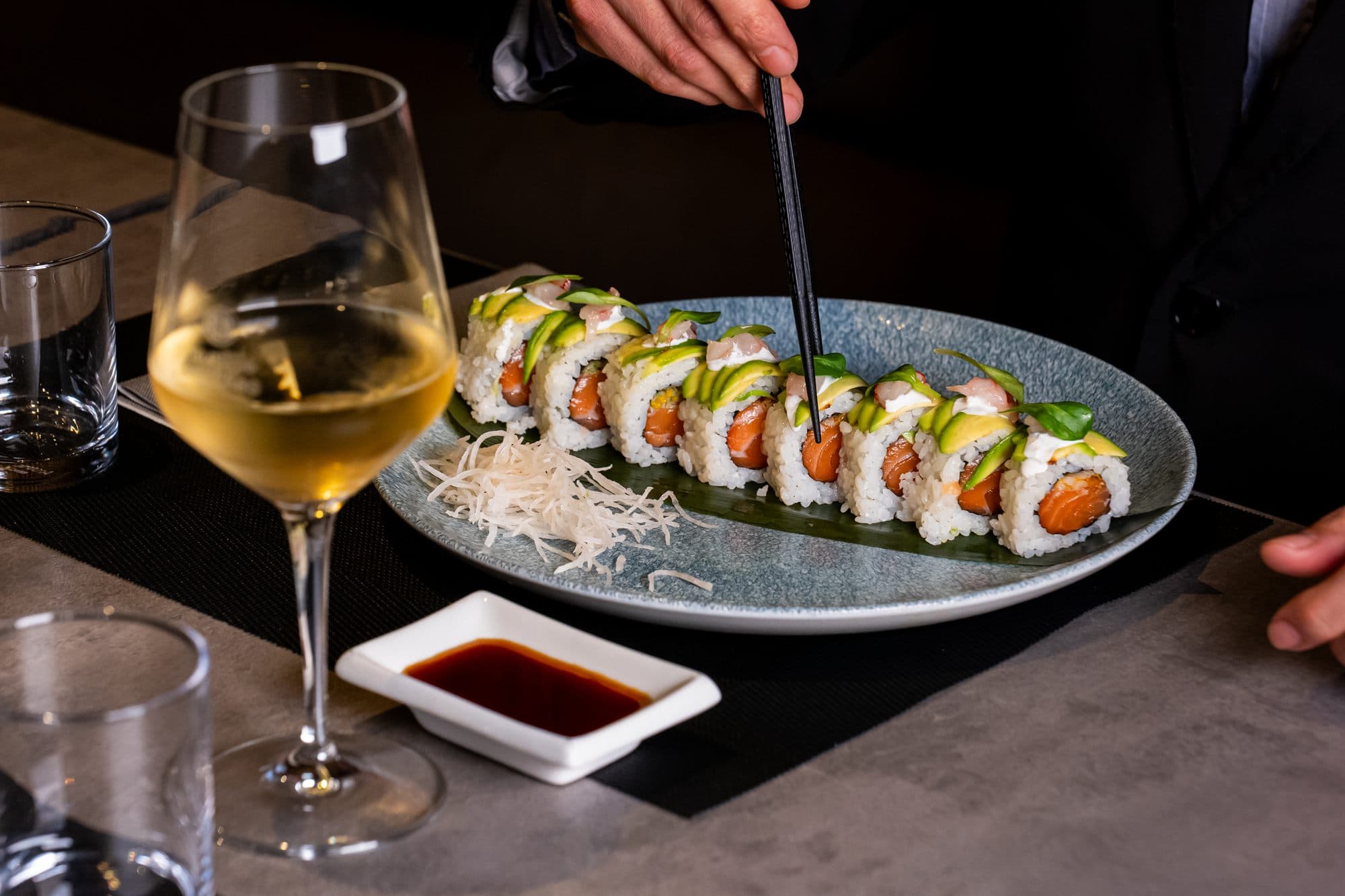 Uramaki serviti al tavolo con un calice di vino bianco