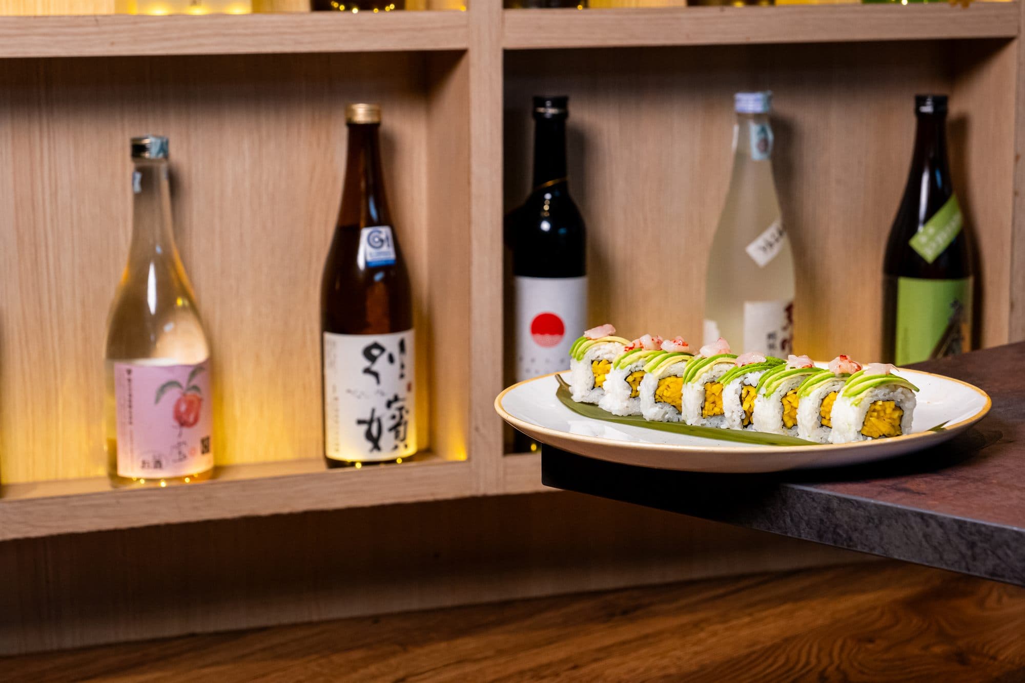 Uramaki serviti davanti alle bottiglie di sake