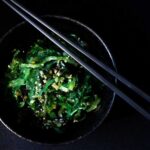 alghe giapponesi wakame in ciotola nera con bacchette nere