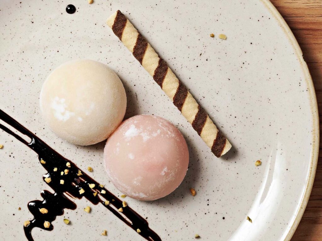piatto bianco con due mochi giapponesi e un biscotto a forma di cannuccia