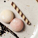 piatto bianco con due mochi giapponesi e un biscotto a forma di cannuccia