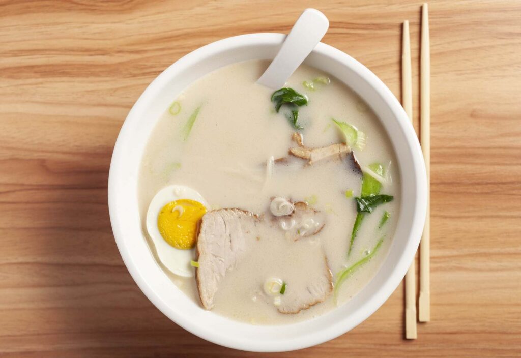 ciotola bianca con ramen in brodo e bacchette