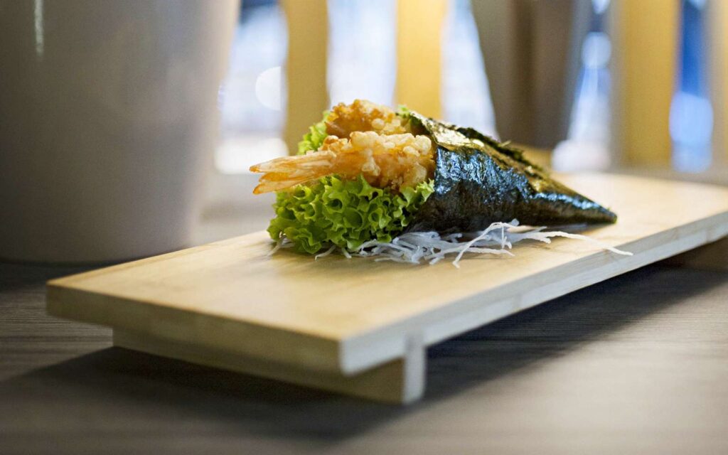 temaki con gambero in tempura su tagliere di legno chiaro